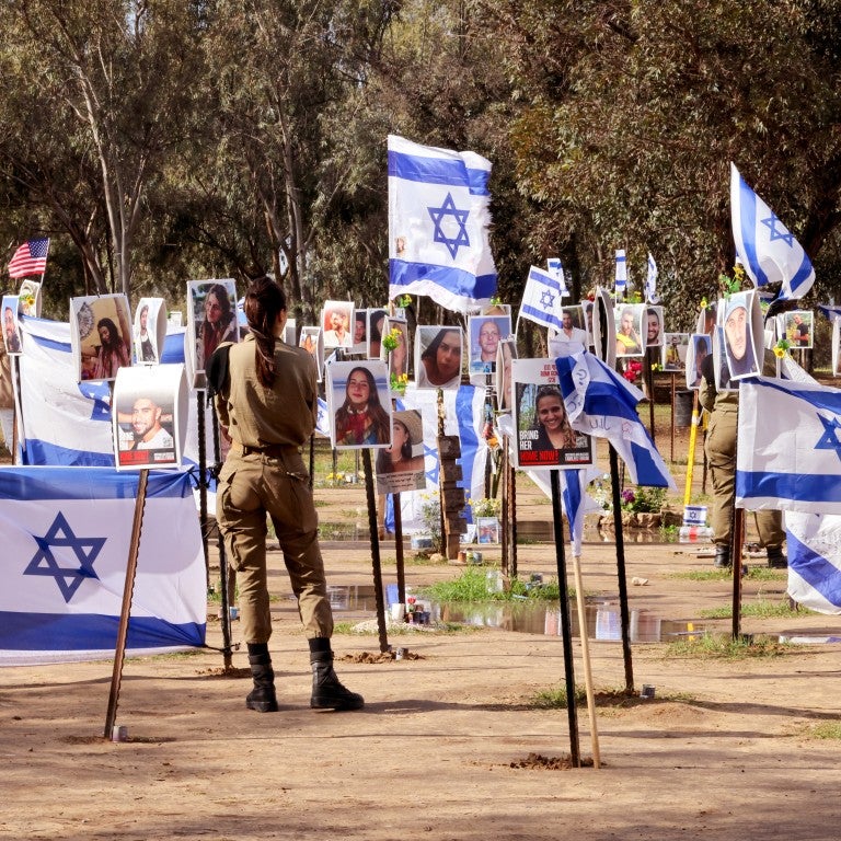 TOPSHOT - Israeli soldiers walk among portraits of people taken captive or killed by Hamas militants during the Supernova music festival on October 7, during a visit at the site where the deadly incident took place near Kibbutz Reim in southern Israel, on January 11, 2024, amid continuing battles between Israel and Hamas in Gaza. 