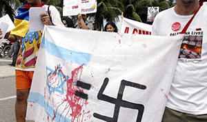 Photo of an Israeli flag, an equals sign, and a swastika with red paint to look like blood
