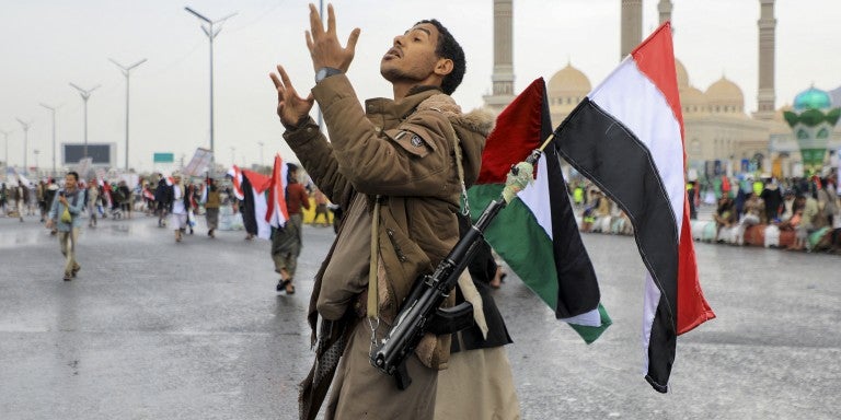 https://ajc.canto.com/b/An armed demonstrator lifting a Palestinian and Yemeni flags gestures during an anti-Israel and anti-US rally in the Huthi-controlled capital Sanaa on January 19, 2024, protesting the US designation of Yemen's Huthi rebels as "terrorists", after a series of attacks on Red Sea shipping amid ongoing battles between Israel and the militant Hamas group in Gaza. 
