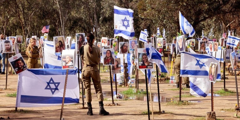 TOPSHOT - Israeli soldiers walk among portraits of people taken captive or killed by Hamas militants during the Supernova music festival on October 7, during a visit at the site where the deadly incident took place near Kibbutz Reim in southern Israel, on January 11, 2024, amid continuing battles between Israel and Hamas in Gaza. 