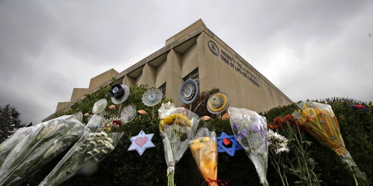 makeshift memorial of flowers, jewish magen david star, rests on bushes outside the Tree of Life Synagogue in Pittsburgh
