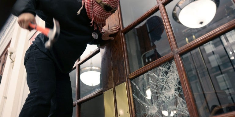 A demonstrator breaks the windows of the front door of the building in order to secure a chain around it to prevent authorities from entering as demonstrators from the pro-Palestine encampment barricade themselves inside Hamilton Hall, an academic building at Colombia University, on April 30, 2024 in New York City. 