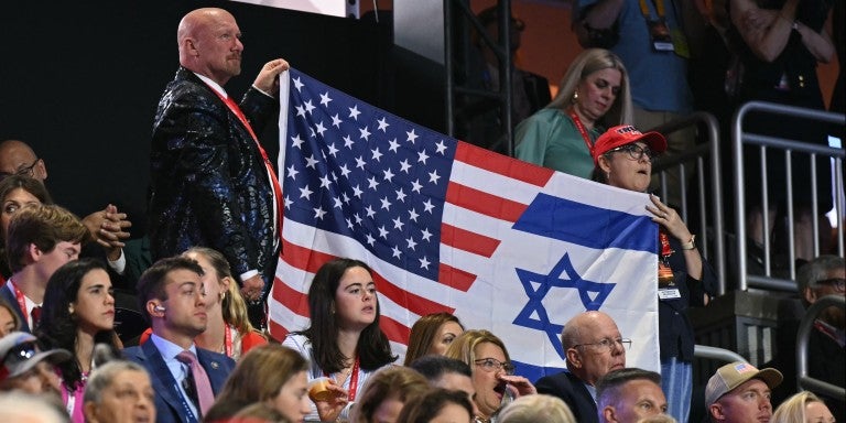 Attendees hold a flag made from the US and Israel flag during the third day of the 2024 Republican National Convention at the Fiserv Forum in Milwaukee, Wisconsin, on July 17, 2024. Days after he survived an assassination attempt Donald Trump won formal nomination as the Republican presidential candidate and picked Ohio US Senator J.D. Vance for running mate. 