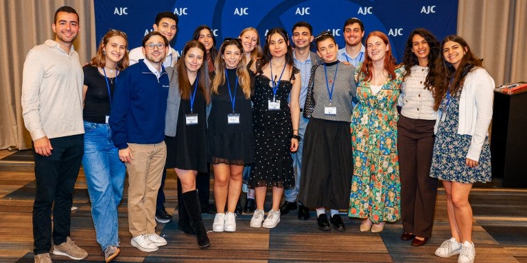 Jewish college students standing in front of an AJC blue background