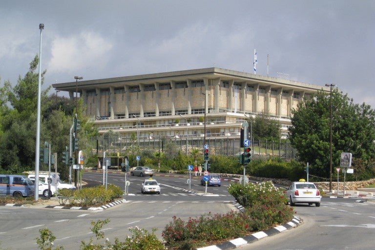 Knessett building israeli parliment. large beige stone building in background, grey-blue sky