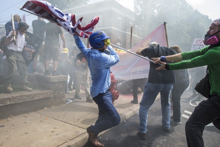 A White Supremacist tries to strike a counter protestor with a White Nationalist flag during clashes at Emancipation Park where the White Nationalists are protesting the removal of the Robert E. Lee monument in Charlottesville, Va., USA on August 12, 2017. 