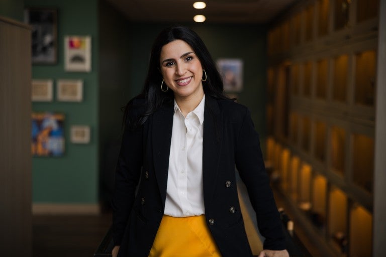 Dr. Mijal Bitton, dressed in a black blazer and yellow skirt and smiling.