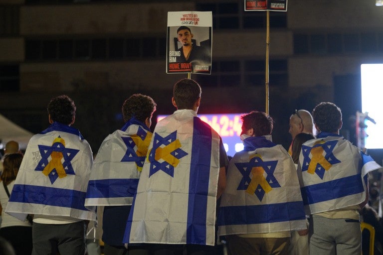  Five people draped in Israeli flags with hostage ribbons on them watch tribute videos while waiting for a live stream of the hostage releases to start at Hostages Square early in the morning on October 13, 2025 in Tel Aviv, Israel. The ceasefire deal between Israel and Hamas has brought an end to the two years of war that followed the attacks of Oct. 7, 2023. A condition of the deal was the immediate return of 48 hostages held in Gaza, around 20 of whom were believed to be alive. 
