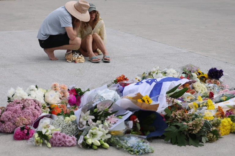 Flowers, israeli flag, two people embracing in anguish