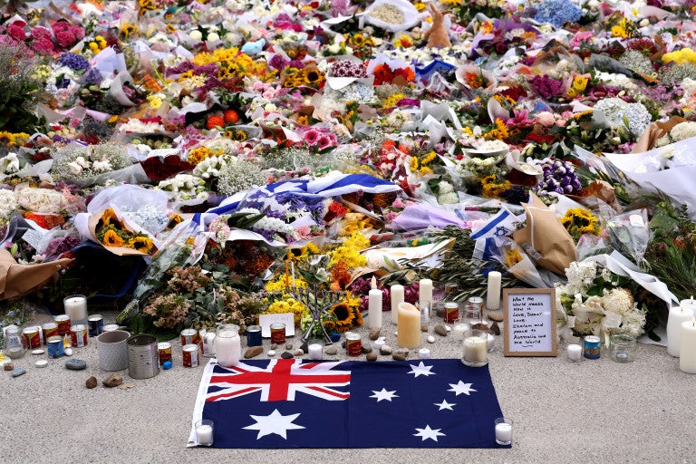 Flowers and an Australian flag are laid in memory of the victims of a shooting at Bondi Beach outside the Bondi Pavilion in Sydney on December 16, 2025. A father-and-son team toting long-barrelled guns shot and killed 15 people including a 10-year-old girl at Sydney's Bondi Beach on December 14, with authorities labelling it an antisemitic terrorist attack on a Jewish festivall