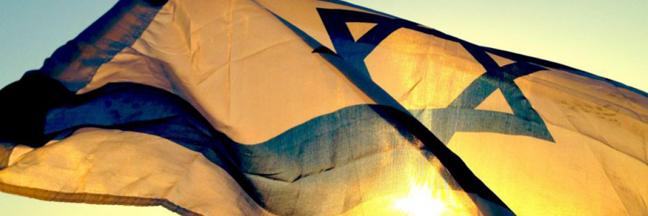 Israeli flag waving in the wind with sunrise in background