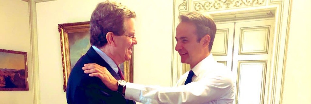 David Harris and PM Kyriakos Mitsotakis embracing