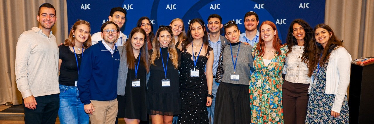 Jewish college students standing in front of an AJC blue background