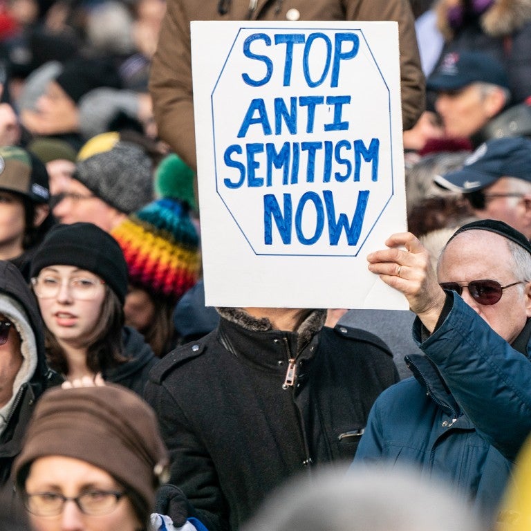 Man holding a sign saying "Stop Antisemitism Now"