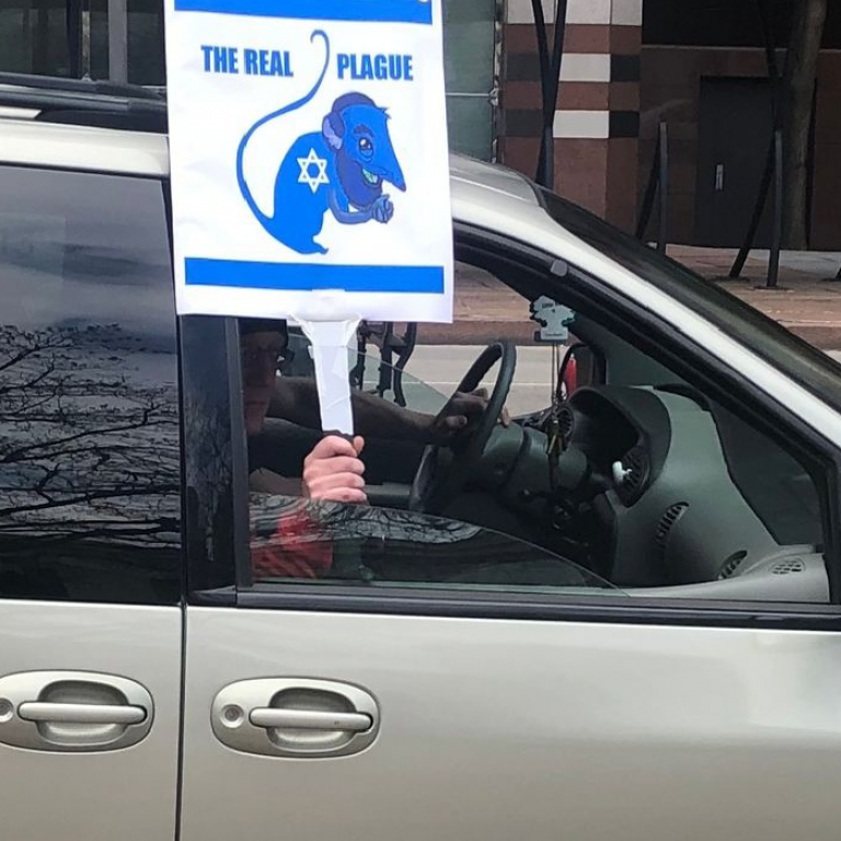 A driver in Ohio holds an antisemitic sign out the window while protesting a stay at home order, photo credit Cleveland News.