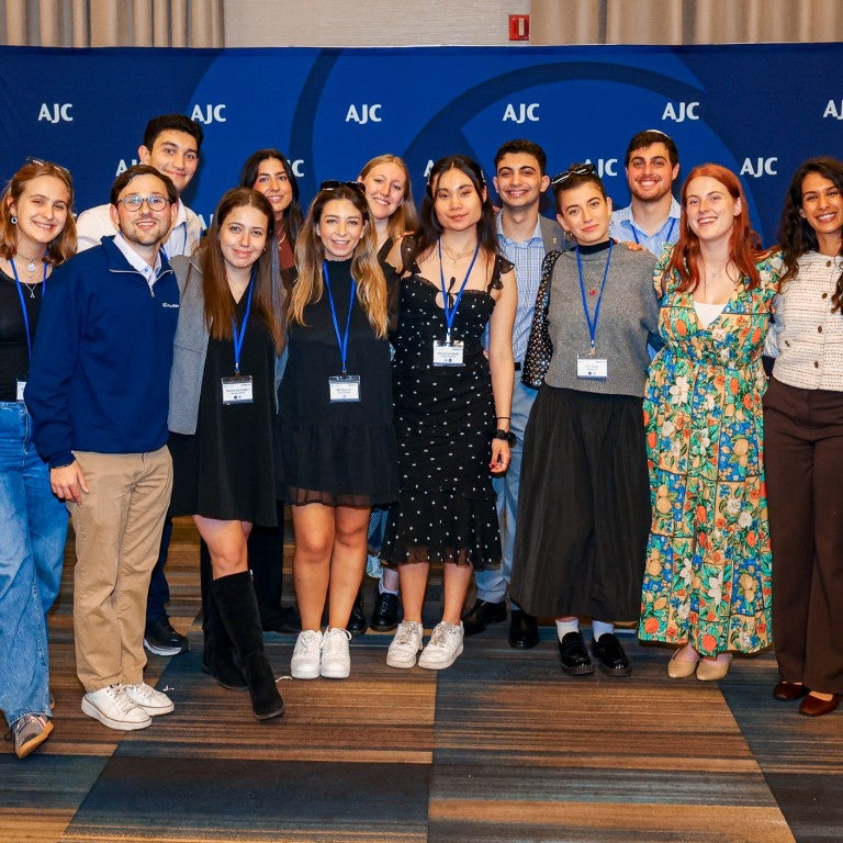 Jewish college students standing in front of an AJC blue background