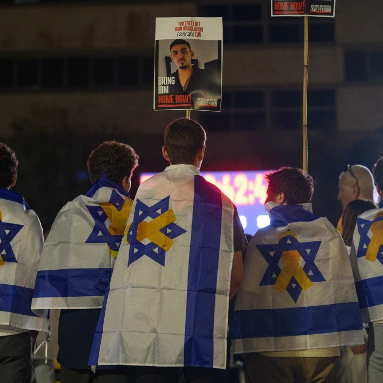  Five people draped in Israeli flags with hostage ribbons on them watch tribute videos while waiting for a live stream of the hostage releases to start at Hostages Square early in the morning on October 13, 2025 in Tel Aviv, Israel. The ceasefire deal between Israel and Hamas has brought an end to the two years of war that followed the attacks of Oct. 7, 2023. A condition of the deal was the immediate return of 48 hostages held in Gaza, around 20 of whom were believed to be alive. 