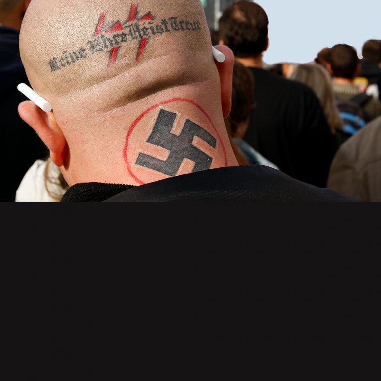 Photo of a man with a shaved head and a Swastika tattoo on the back of his neck